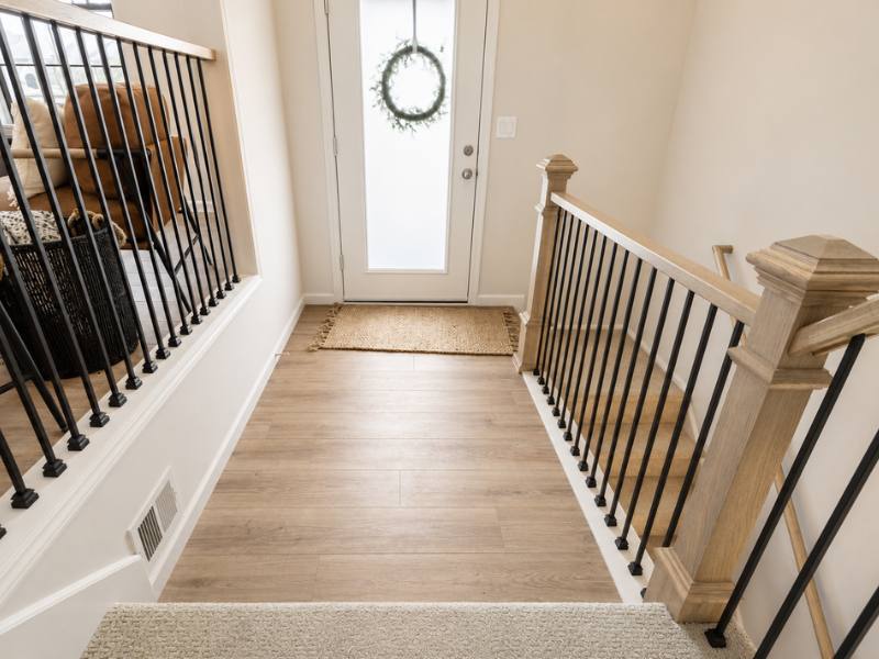Light oak LVP flooring in a home entryway with black railings